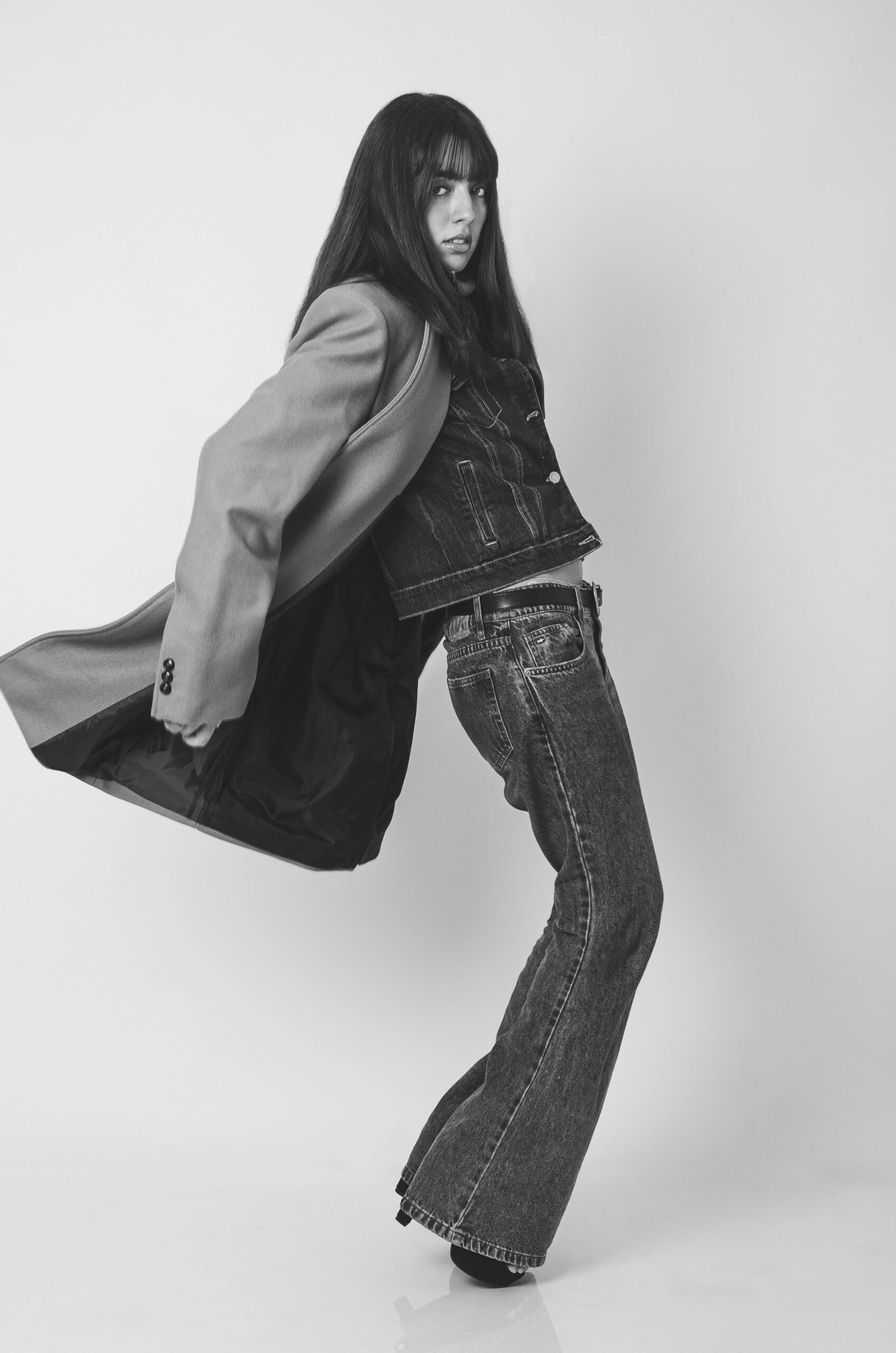 Young woman posing in denim outfit in monochrome fashion shoot, featuring patola print kurtis.