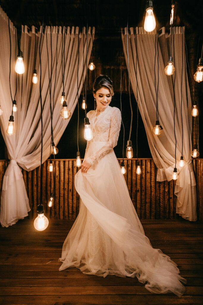 A stunning bridal photoshoot featuring a model in a white gown surrounded by hanging lights and curtains.